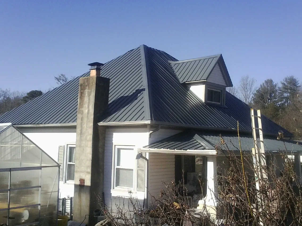 Dark blue standing seam metal roof on a white farmhouse with dormer — Slate & Tile Roof Repair by Roofing Brothers in Alberton