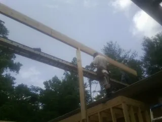 Carpenter setting a ridge beam over a new addition frame — Ice Dam Removal by Roofing Brothers in Alberton
