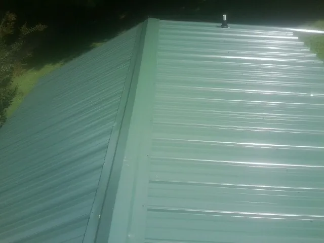 New green metal panels meeting at the ridge of a roof — Flat Roof Repair work by our crew in Alberton