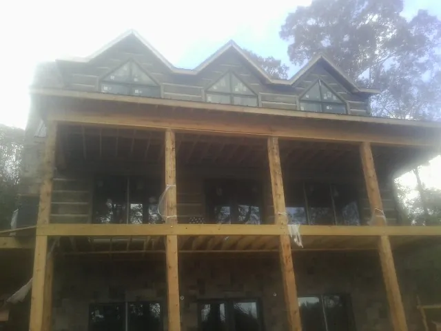 Dormers and porch framing on a large log home under construction — Roof Coating work by our crew in Alberton