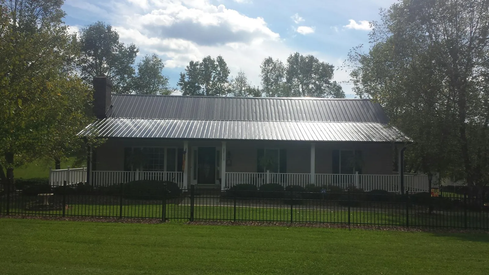 Gray metal roof on a brick ranch with a full width front porch — Gutter Guard Installation work by our crew in Alberton