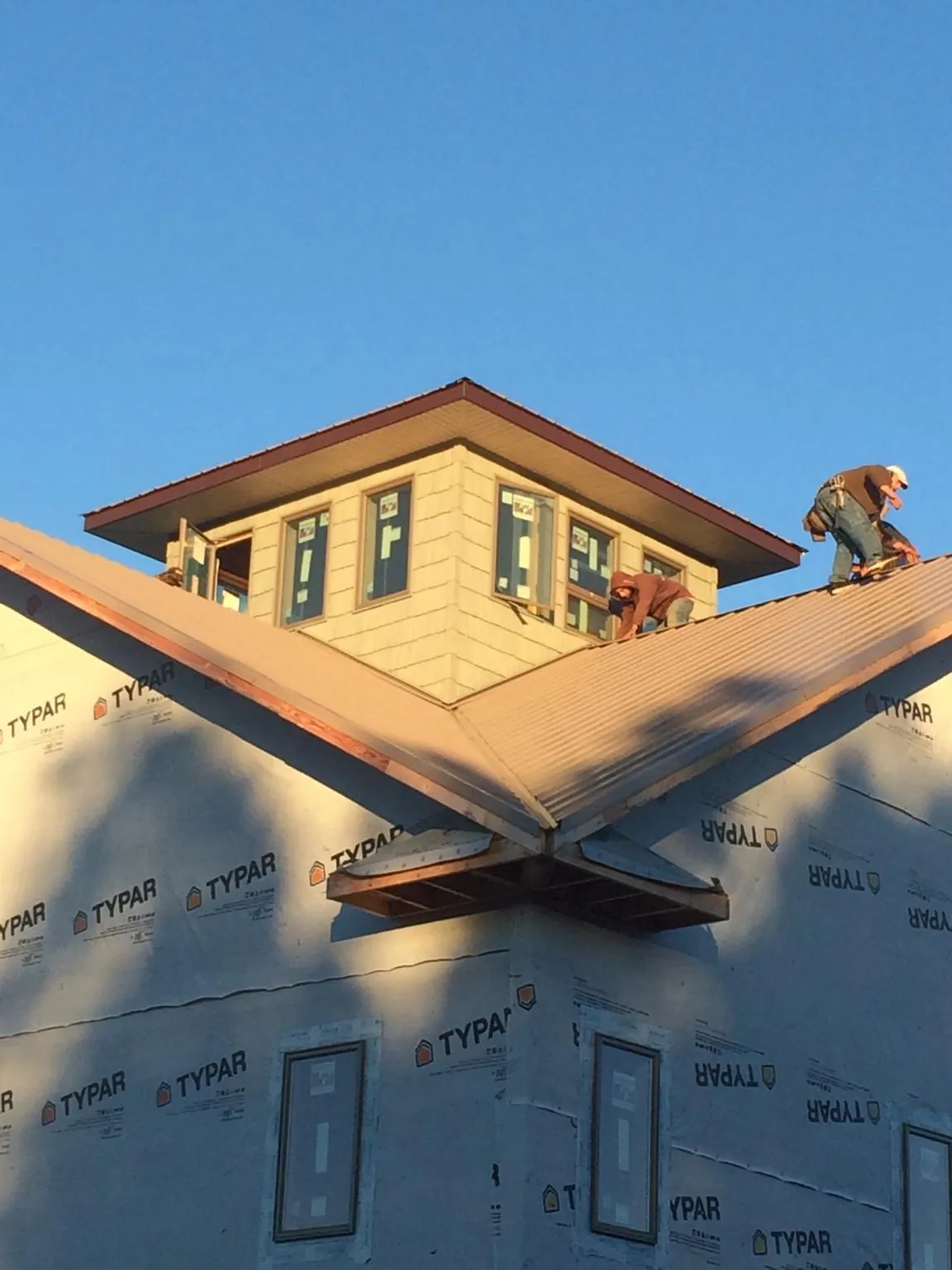Roofers working around a rooftop cupola on a new metal roof at sunset — Roof Waterproofing in Alberton by Roofing Brothers
